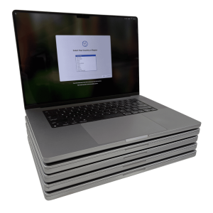 Five silver laptops stacked, the top one open and showing a setup screen.